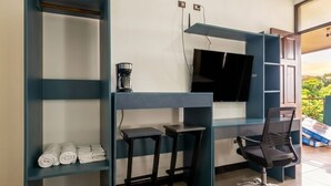 A modern office space with a desk, two chairs, a coffee machine, and a TV mounted on the wall. - Congos Hotel (Aguas Zarcas)