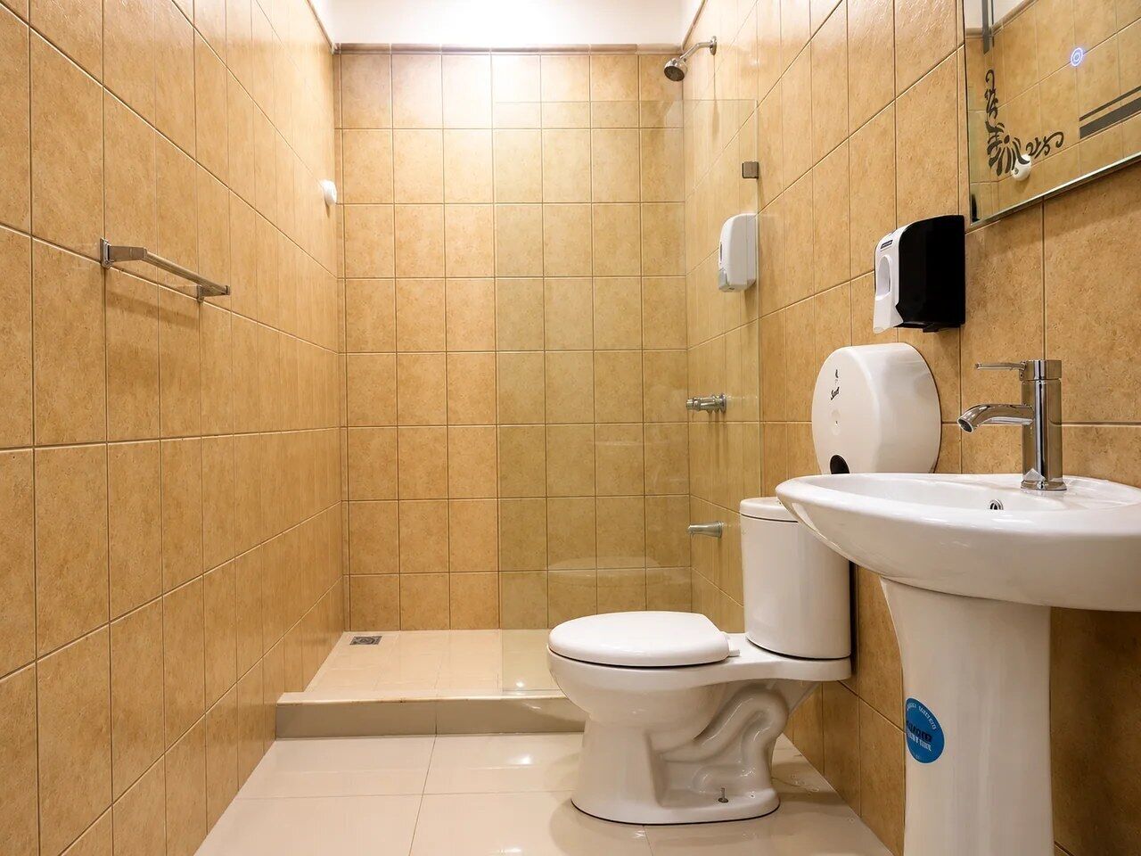 Un baño con inodoro blanco, lavamanos y zona de ducha.
