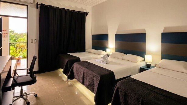 A hotel room with two beds, a desk, and a chair. - Congos Hotel (Aguas Zarcas)