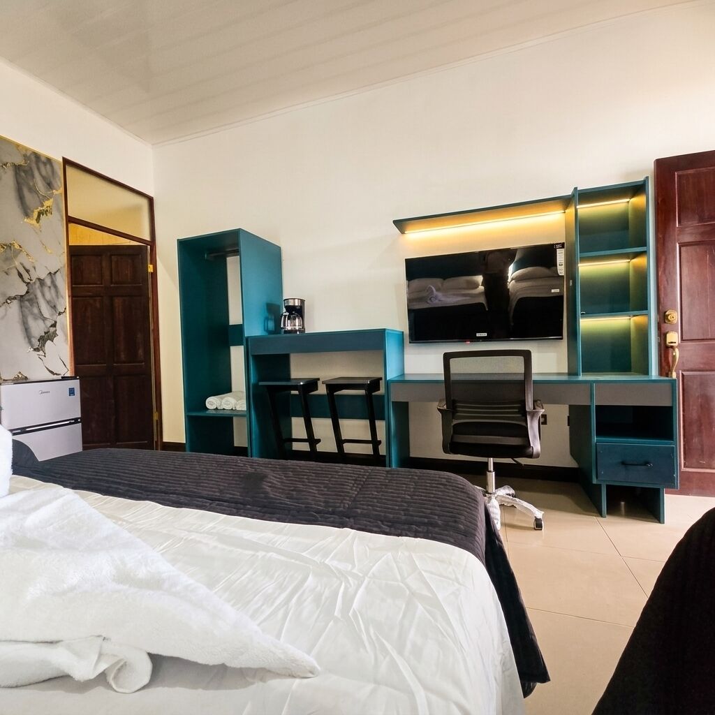Une chambre d’hôtel comprenant un lit, un bureau avec une chaise, une télévision et un minibar.