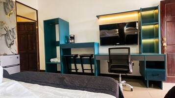 Une chambre d’hôtel comprenant un lit, un bureau avec une chaise, une télévision et un minibar.