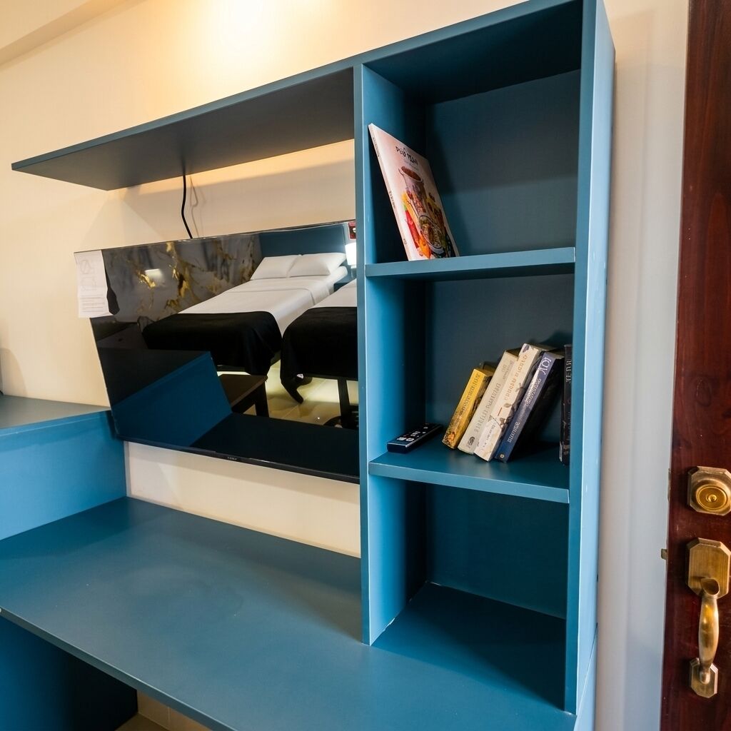 A room with a blue wall-mounted shelf unit containing books and a remote control.