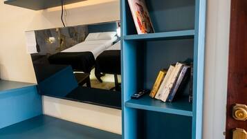 A room with a blue wall-mounted shelf unit containing books and a remote control.