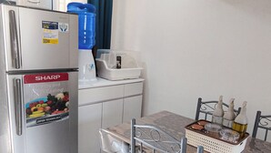 Una cucina compatta con frigorifero, erogatore d'acqua e tavolo con sedie.