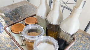 Un vassoio con barattoli e bottiglie su un tavolo con tovaglia decorata.