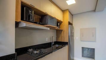 Una cocina moderna con estufa a gas, microondas y refrigerador.