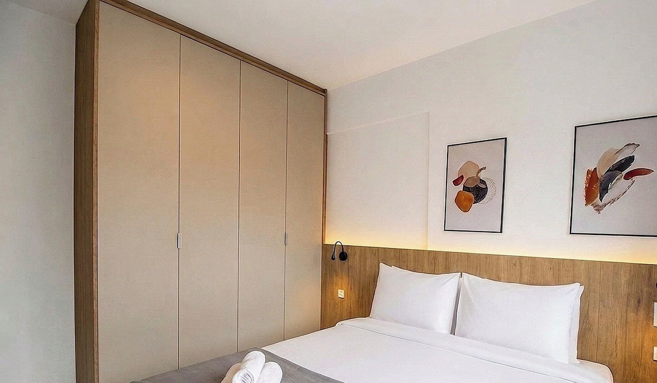 Une chambre d’hôtel comprenant un lit, une armoire et deux œuvres d’art accrochées au mur.