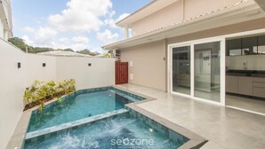 Ein modernes Haus mit Swimmingpool, Glastür-Eingang und Küchenbereich.