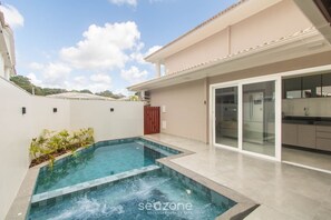 Ein modernes Haus mit Swimmingpool, Glastür-Eingang und Küchenbereich.