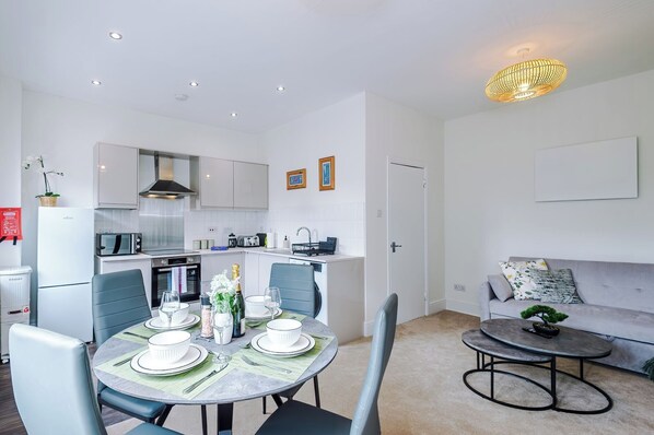 A compact living space with a dining area, kitchenette, and a seating area with a sofa and coffee table.