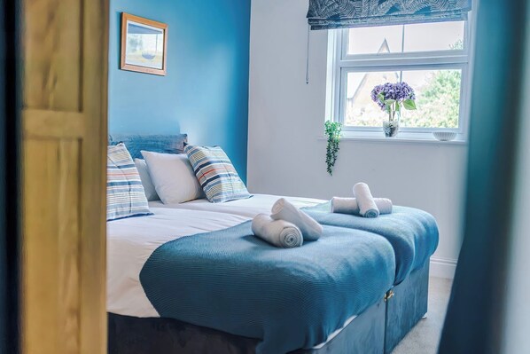 Un dormitorio con cama, almohadas, una ventana con vistas y una planta colgante.