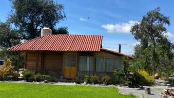 Una casa de un piso con techo de tejas rojas, un porche delantero y un césped bien cuidado.