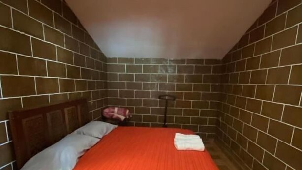 Ein Zimmer mit einem Bett, einem Fenster und einer Backsteinwand.