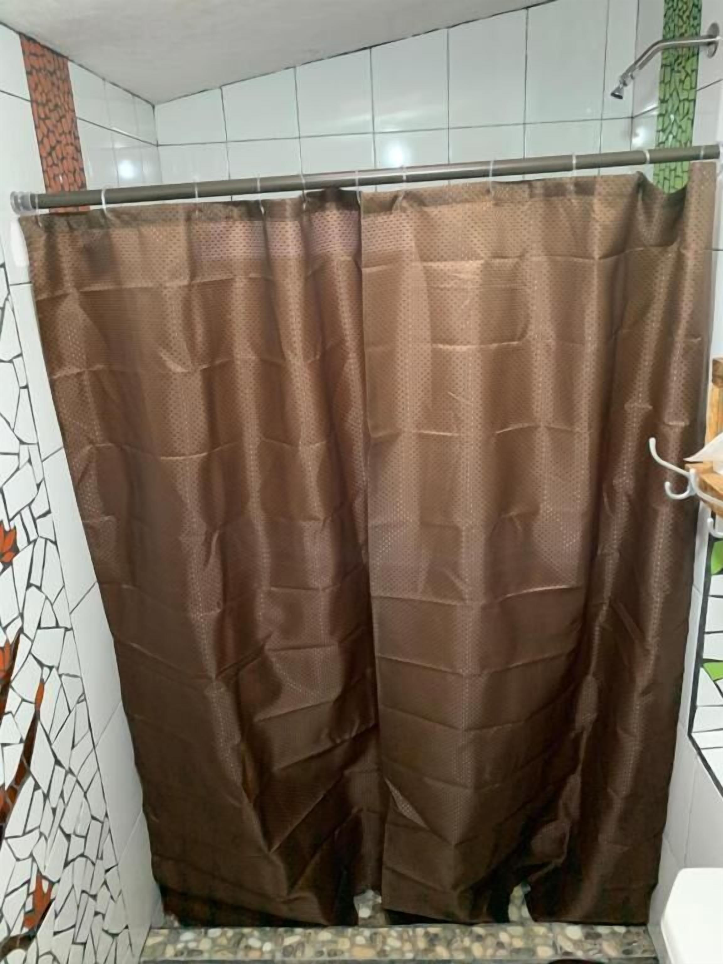 A bathroom with a shower curtain, tiled walls, and a toilet.