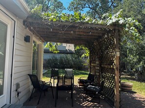 Ein überdachter Patio-Bereich mit einer Holzhütte, Sitzgelegenheiten im Freien und Blick auf den Garten.