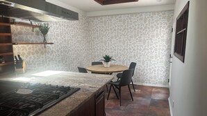 Una cocina moderna con una isla central, un comedor con una mesa redonda y un papel tapiz estampado.