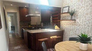 Una cocina moderna con una isla central, taburetes de bar y una mesa de comedor.