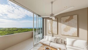 A modern living room with a large sliding glass door leading to a balcony with a scenic view. - Praia Suites by Avia Suites (Santa Marta)