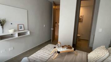 En moderne stue med en sofa, et sofabord med en bakke og en vægmonteret hylde med pyngeting.
