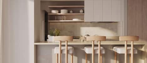 Cocina moderna con una isla central, taburetes de bar y una mesa de comedor con revistas.