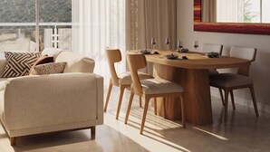 A modern living room with a sofa, dining table, chairs, and a large window with a view. - Praia Suites by Avia Suites (Santa Marta)