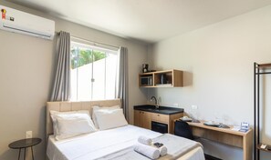 Ein Hotelzimmer mit einem Bett, einem Schreibtisch, einem Waschbecken und einem Fenster mit Vorhängen.