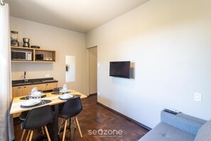 Um espaço compacto com área de refeições, cozinha compacta e televisão fixada na parede.