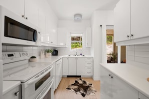 A modern kitchen with white cabinetry, a built-in microwave, a stove, and a sink. - L'Après-Ski Mont-Tremblant (Mont-Tremblant)