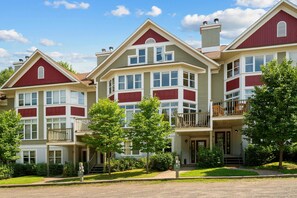 A row of multi-story residential buildings with a consistent architectural style, featuring bay windows and a combination of red and beige siding. - L'Après-Ski Mont-Tremblant (Mont-Tremblant)