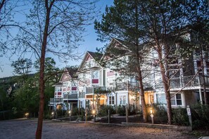 A multi-story hotel with balconies, a well-lit entrance, and a parking area. - L'Après-Ski Mont-Tremblant (Mont-Tremblant)
