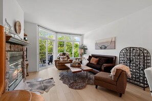 Un salon spacieux avec une cheminée, une grande fenêtre et un coin salon confortable.