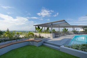 Et tagområde med pool, pergola, liggestole og udsigt over bybilledet.
