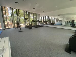 Et fitnesscenter med løbebånd, spejle og store vinduer.