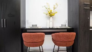 A modern kitchen with two orange chairs, a white vase with flowers, and a dark wooden cabinet. - Executive Studio at LoxwoodHouse, East Legon (Accra)