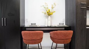 A modern kitchen with two orange chairs, a white vase with flowers, and a dark wooden cabinet. - Executive Studio at LoxwoodHouse, East Legon (Accra)