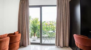A room with a sliding glass door leading to a balcony with a table and chairs, and two sofas. - Executive Studio at LoxwoodHouse, East Legon (Accra)