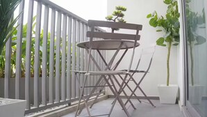 A balcony with a folding chair, a potted plant, and a white railing. - Executive Studio at LoxwoodHouse, East Legon (Accra)