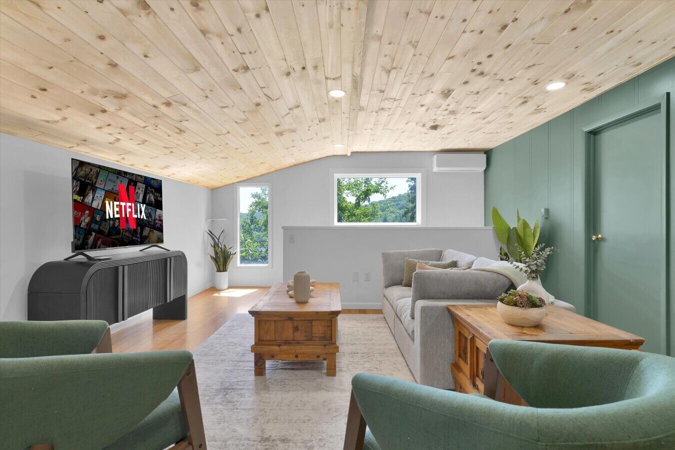 Una sala de estar moderna con techo de madera, un televisor de pantalla plana grande, un sofá gris y una mesa de centro.
