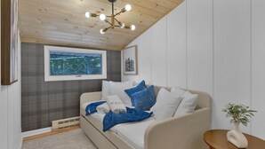 Una habitación con una cama, una ventana con vistas, una lámpara de techo y una pequeña mesa con una planta.