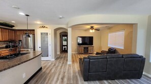 A modern kitchen with a built-in refrigerator, a dining area with a dark leather sofa, and a living room with a flat-screen TV. - Legacy Sports Arizona Family Vacation (San Tan Valley)