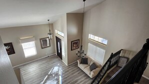 A spacious living area with a staircase, a chandelier, and a sofa with cushions. - Legacy Sports Arizona Family Vacation (San Tan Valley)