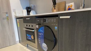 Uma cozinha compacta com máquina de lavar louça embutida, forno e cafeteira na bancada.