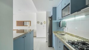 A modern kitchen with blue cabinets, a stainless steel refrigerator, a built-in microwave, and a gas stove. - Apart w/ BBQ in Condo w/ Pool Rmm0206 (Florianópolis)