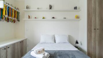 A neatly arranged bedroom with a bed, a nightstand, and a wardrobe.