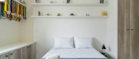 A neatly arranged bedroom with a bed, a nightstand, and a wardrobe.