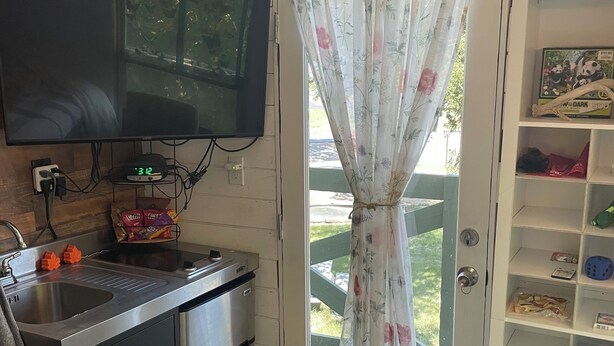 A compact kitchen with a built-in microwave, a sink, and a television mounted on the wall. - Cozy treehouse ! Great kids experience !Or adult ! Fire pit ONLY SLEEPS 2 (Lavon)