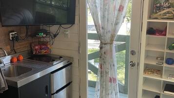 A compact kitchen with a built-in microwave, a sink, and a television mounted on the wall.