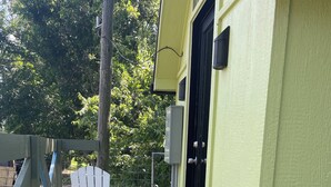 A wooden deck with a white chair and a small table, a door, and a green wall. - Cozy treehouse ! Great kids experience !Or adult ! Fire pit ONLY SLEEPS 2 (Lavon)