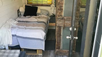 Un dormitorio acogedor con cama, una mesita pequeña y una ventana con diseño de vitral.
