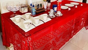 Une table dressée avec des tasses et des soucoupes blanches, et une nappe rouge.